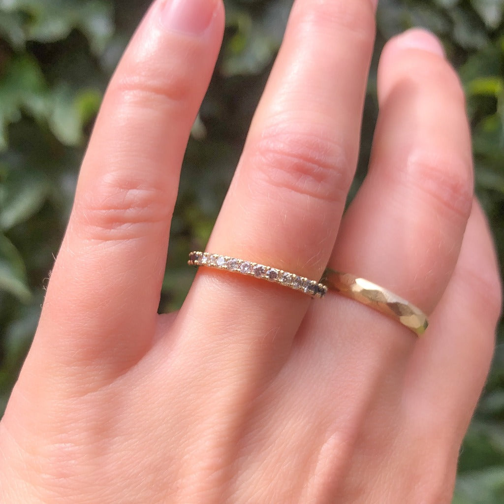 Light pink natural diamond ring with salt and pepper and black diamonds in 18k yellow gold on hand with a faceted gold ring